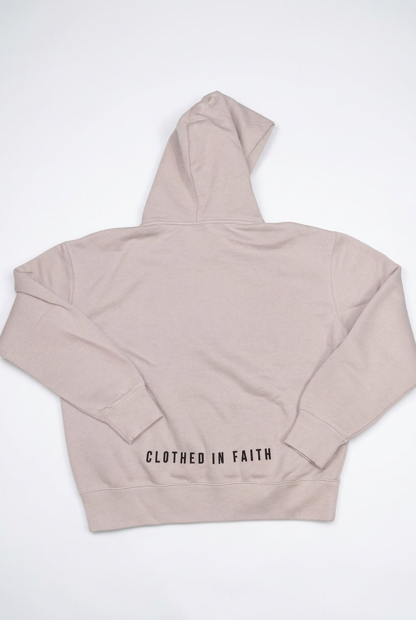 Beige hoodie with 'Clothed in Faith' text on a light gray background