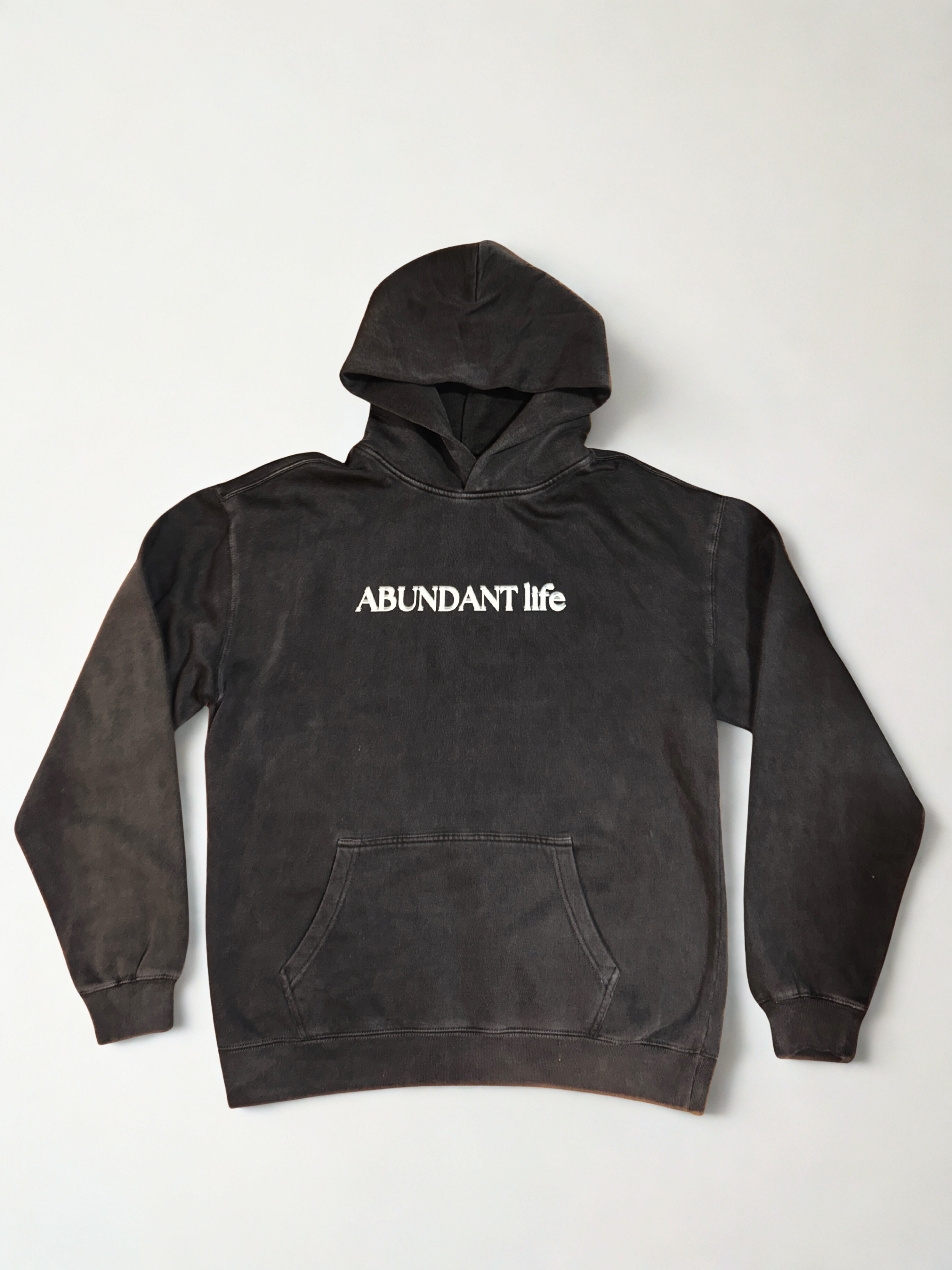 Black hoodie with 'ABUNDANT life' text on a white background